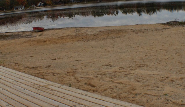 Relax at a newly restored lakefront home with a sandy beach and calm waters.